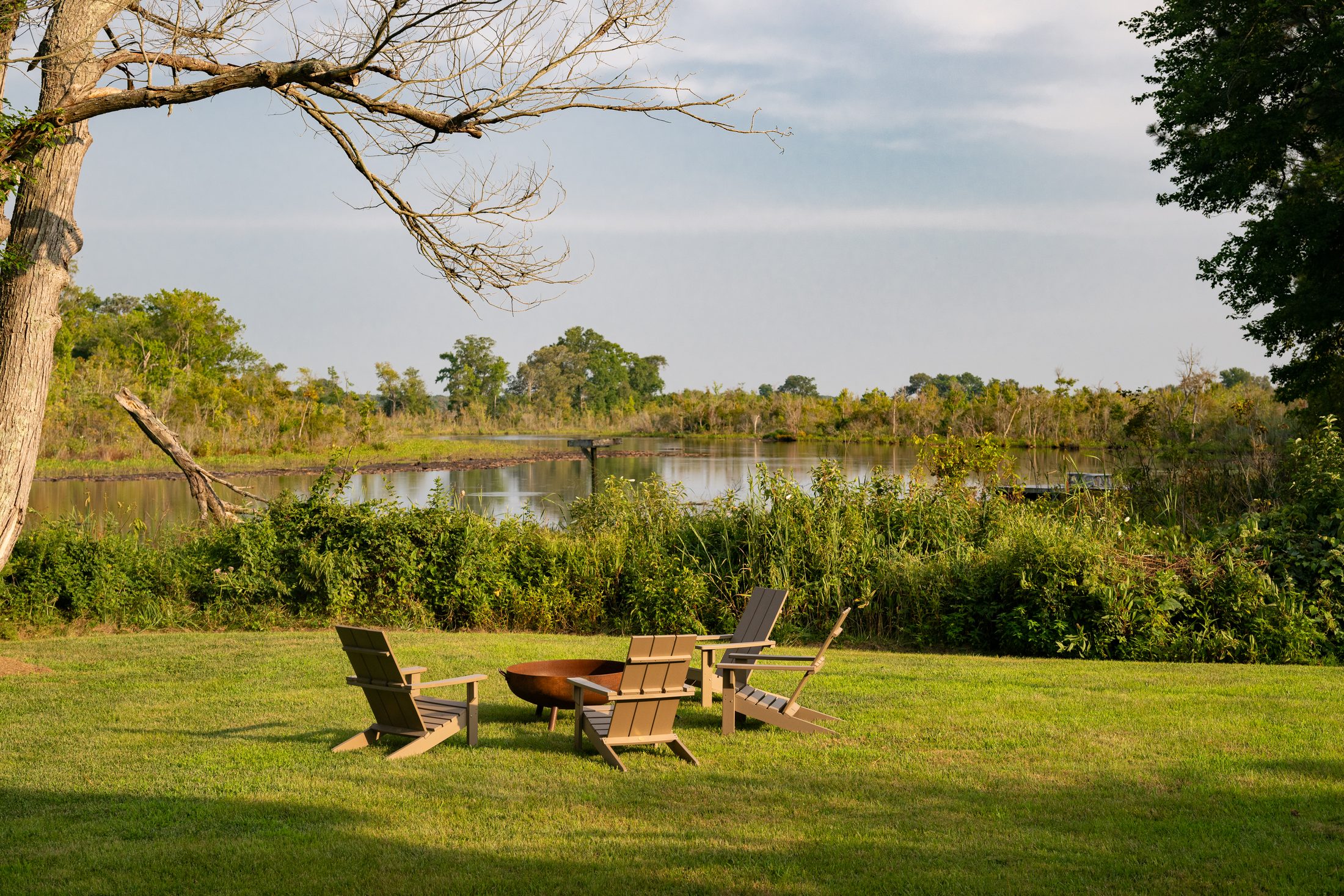 Wood-burning fire pit with Adirondack chairs at the edge of the water