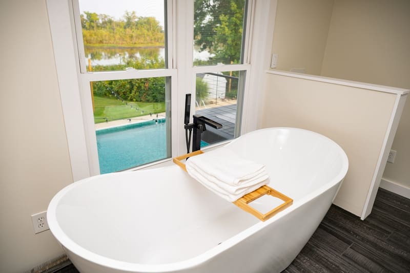 Soaking tub with folded towels and a view of the pool