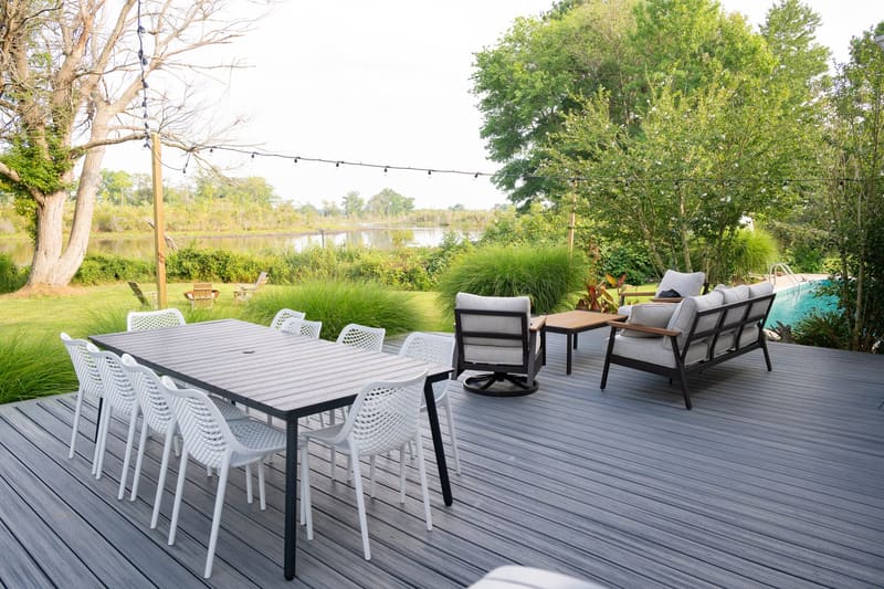 Outdoor dining table for ten on the deck beneath string lights