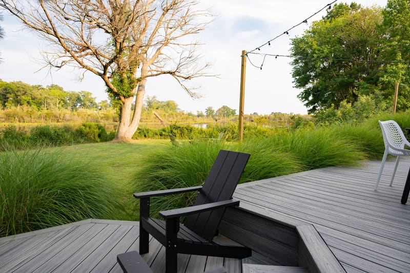 A single deck chair facing the lawn at golden hour