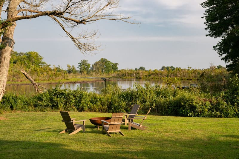 Wood-burning fire pit with Adirondack chairs at the edge of the water