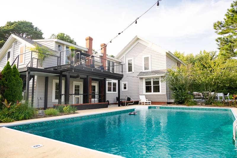 The in-ground pool and rear of the farmhouse under string lights